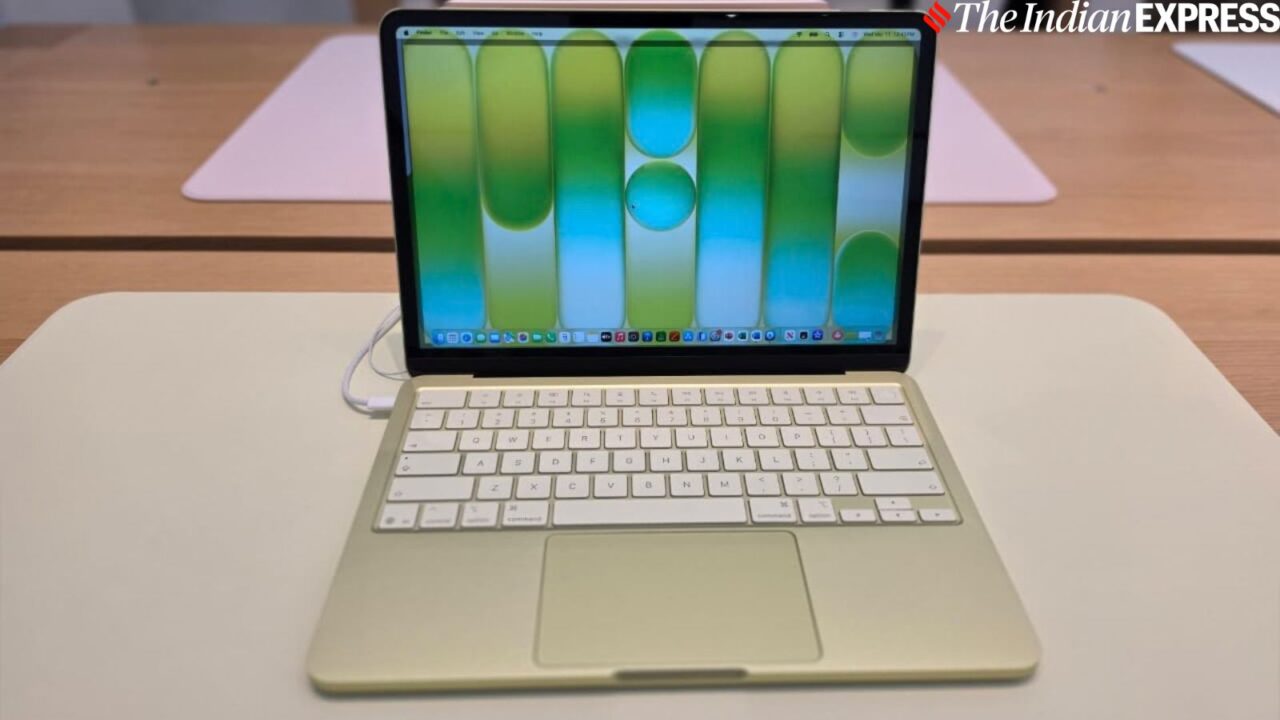 1000040773 Gold-colored laptop on a white desk, open to a bright blue‑green wallpaper with The Indian Express watermark in the corner.